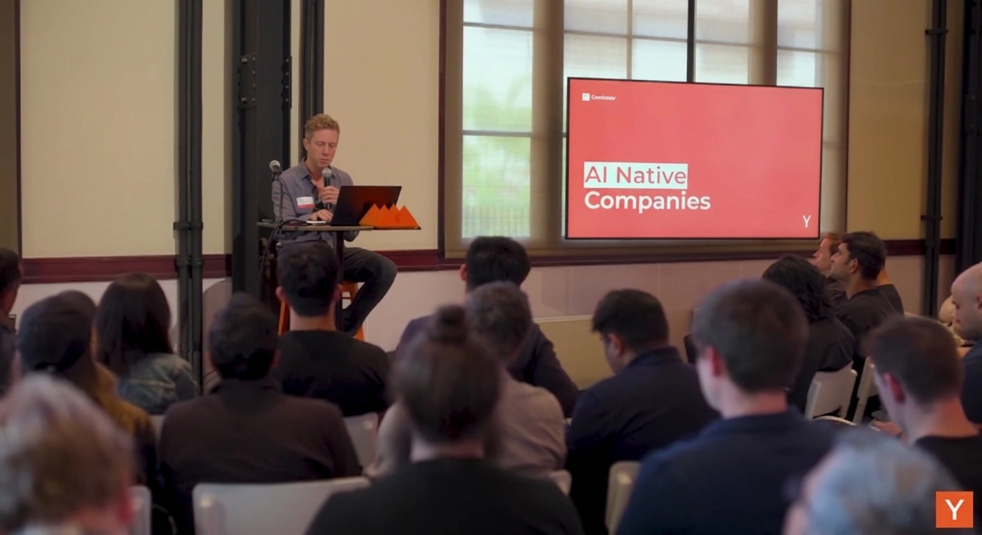 Tom Blomfield 在 YC 演讲现场，屏幕上显示 AI Native Companies